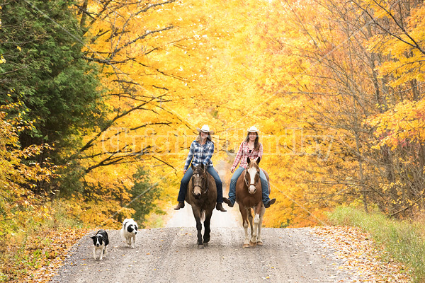 Two young women horseback riding through autumn colored scenery