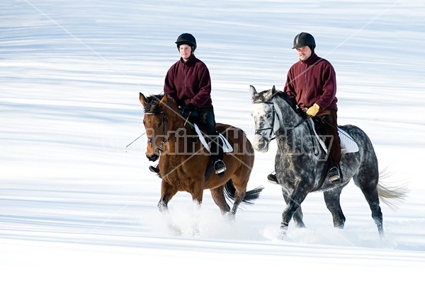 Husband and wife horseback riding through the deep snow