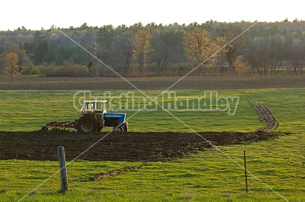 Farmer plowing field in the spring of the year with tractor and a three furrow plow