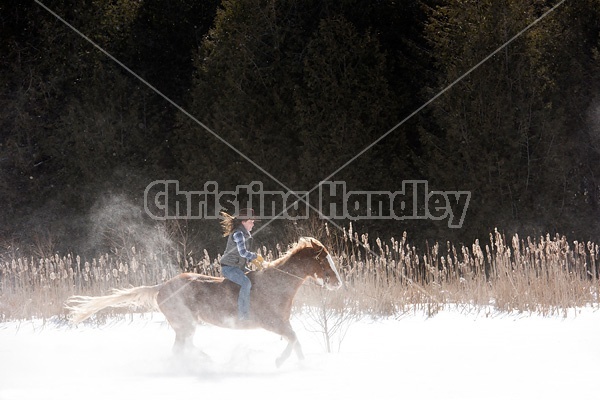 Young woman riding a horse bareback through deep snow