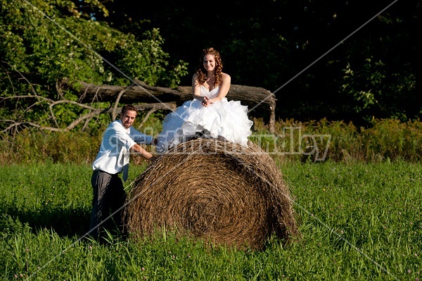 Bride and groom on round bale of hay 