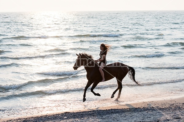 Young woman horseback riding in the surf of Lake Ontario. 