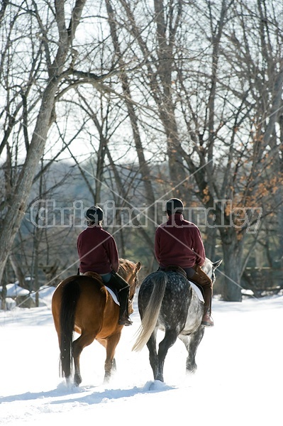 Husband and wife horseback riding through the deep snow