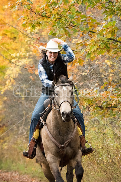 Young woman riding a Quarter Horse on trail