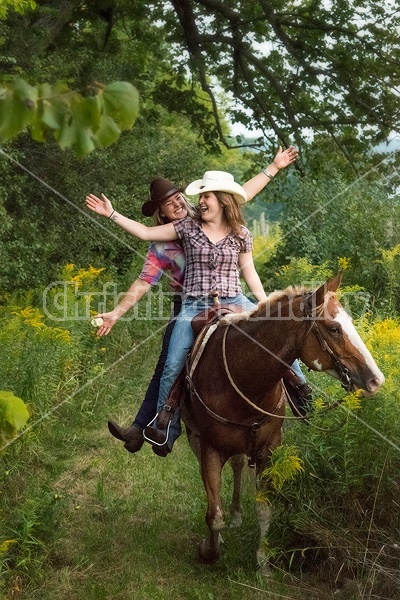 Two young women riding double in a western saddle