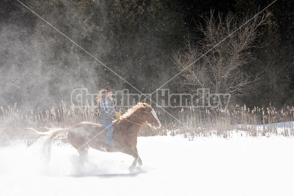 Young woman riding a horse bareback through deep snow