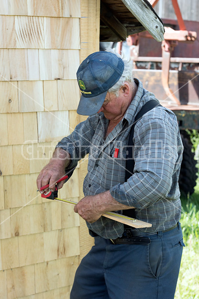 Man putting cedar shingles on the wall of a barn