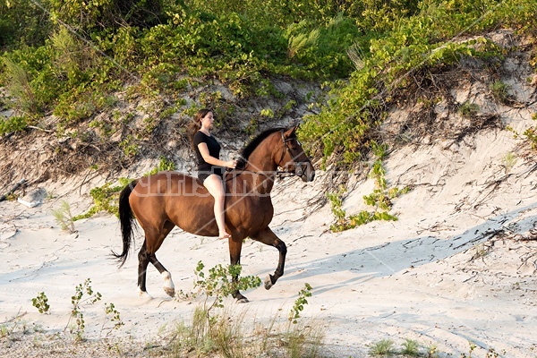 Young woman riding a hrose bareback in the sand