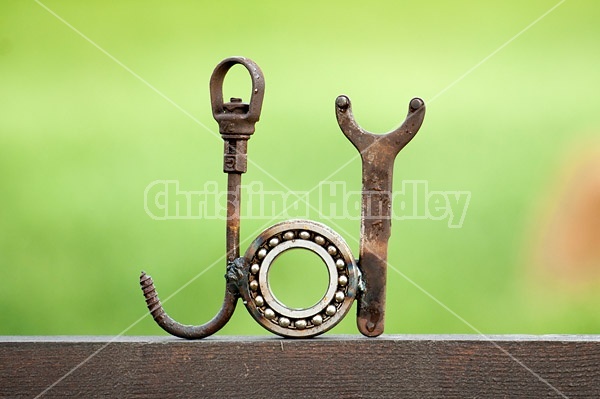 Hand crafted joy garden art sign made out of recycled or repurposed farm tools and machinery parts then welded together