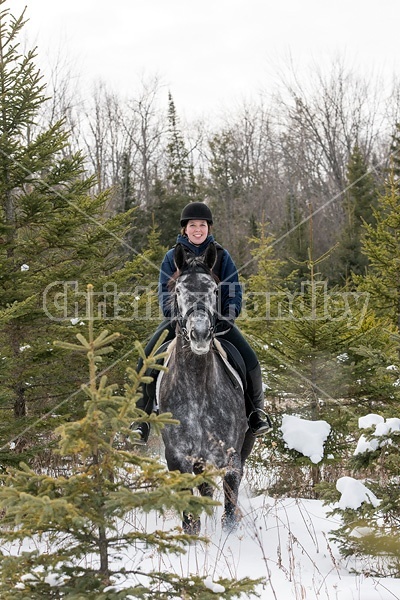 Woman riding Hanoverian mare through forest