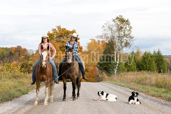 Two young women horseback riding through autumn colored scenery