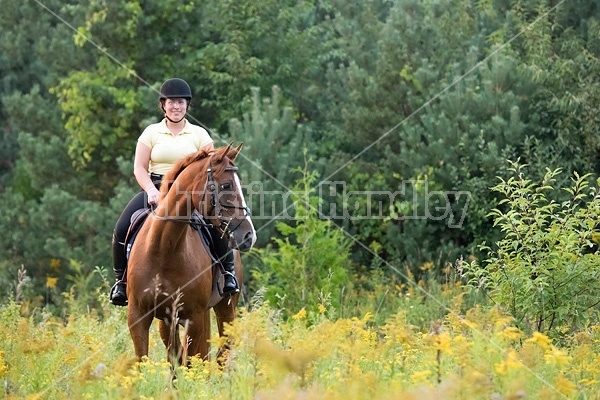 Young woman riding chestnut Thoroughbred horse.