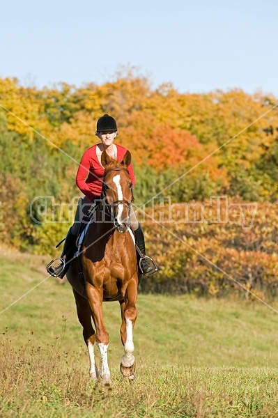 Young woman horseback riding in the fall of the year.