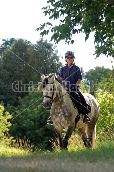Woman riding gray horse in field