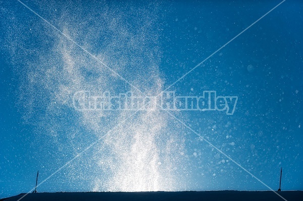 Photo of wind blowing snow over top of barn roof