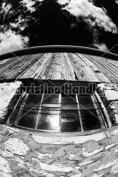 Infrared photo of barn window and wall shot up towards the sky.