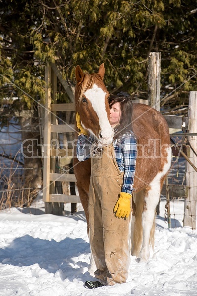 Young woman standing and hugging her horse