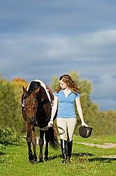 Young girl leading her horse down a grass path