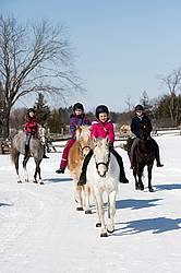 Four young girls riding their ponies bareback in the snow