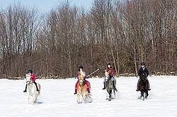 Four young girls riding their ponies bareback in the snow