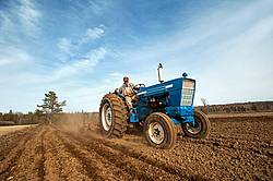 Farmer driving tractor working up field with cultivator