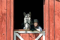 Young woman in barn doorway with horse