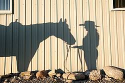Shadow of woman and western horse on the side of barn