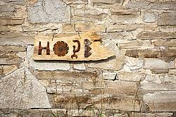 Hand made Hope garden art sign hanging on a barn stone wall