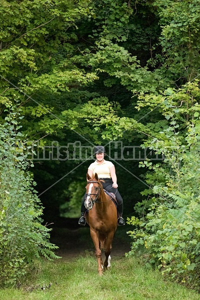 Young woman riding chestnut Thoroughbred horse.