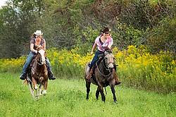 Two young women racing on horseback