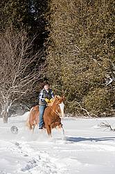 Young woman riding a horse bareback through deep snow
