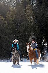 Two young woman riding horses bareback through deep snow