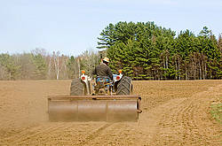 Farmer driving tractor pulling a land roller