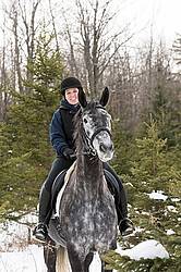 Woman riding Hanoverian mare through forest