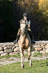 Young woman riding palomino horse
