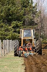 Farmer plowing field in the spring of the year with tractor and a three furrow plow