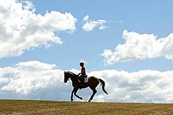 Woman horseback riding against big sky background