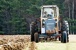 Farmer plowing field in the spring of the year with tractor and a three furrow plow