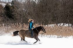 Young woman riding a horse bareback through deep snow