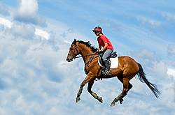 Woman riding bay horse in the clouds