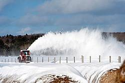 Snow blowing a road with tractor