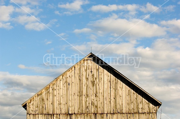 Barn pictured against big blue sky with puffy clouds