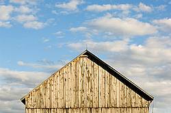 Barn pictured against big blue sky with puffy clouds